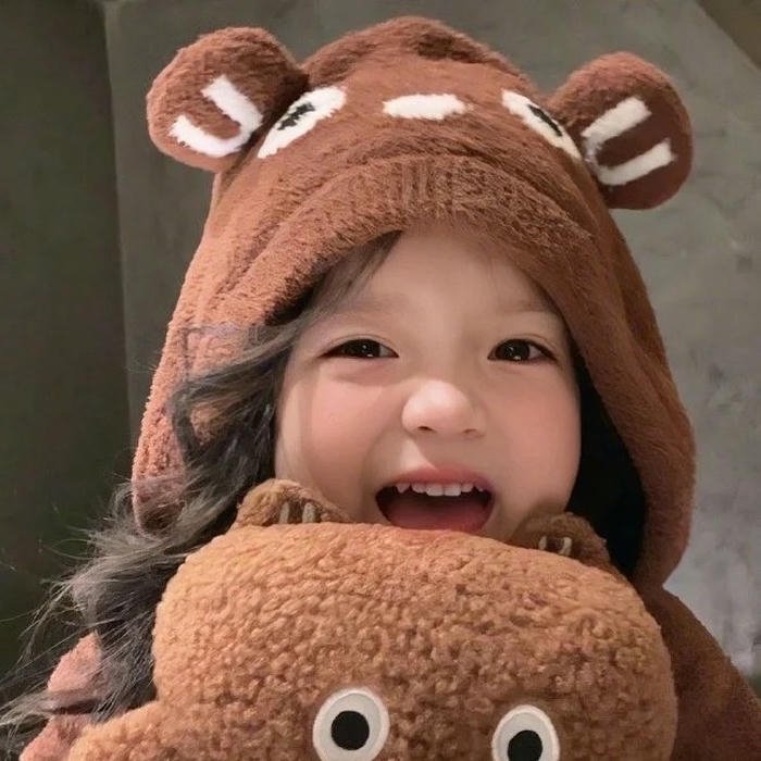 Hình nền em bé đội mũ gấu nâu cười tít mắt