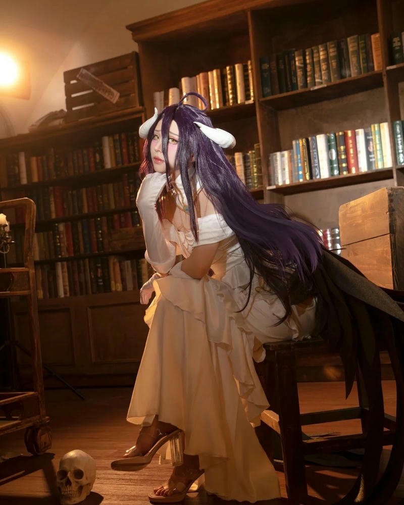 Ảnh cosplay Albedo váy trắng đứng trong căn phòng ấm cúng