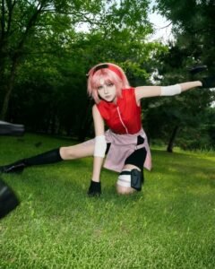 Sakura Tóc Hồng ngồi xổm trên thảm cỏ xanh