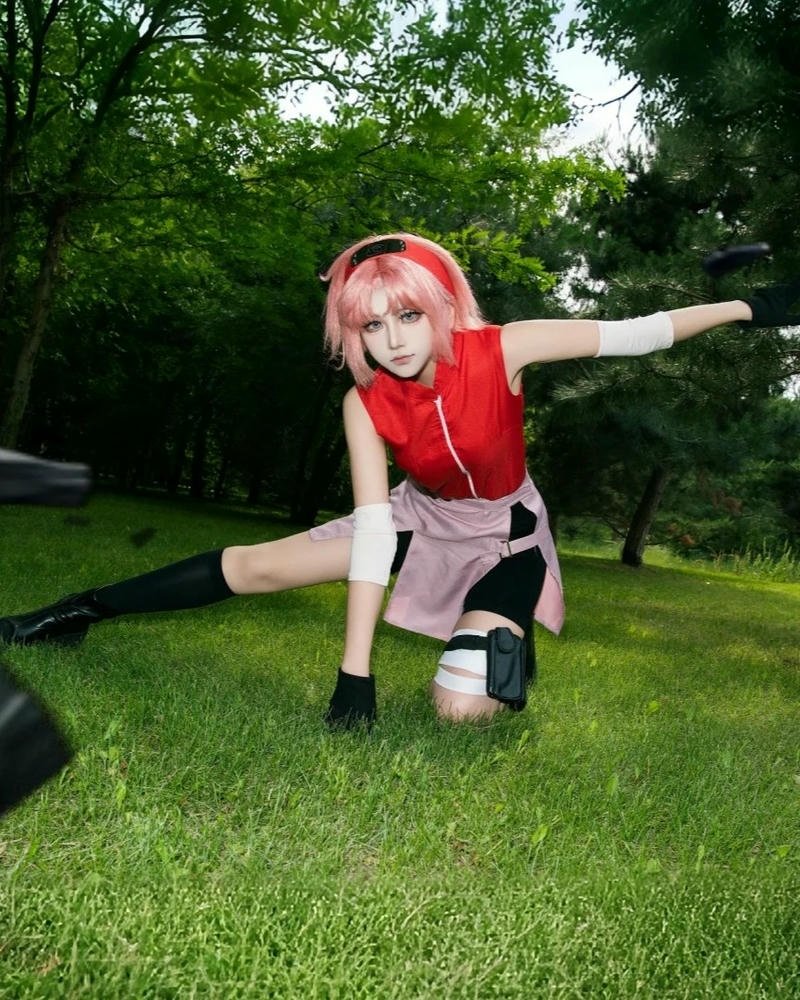 Sakura Tóc Hồng ngồi xổm trên thảm cỏ xanh